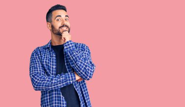 Gündelik kıyafetler giyen genç İspanyol adam kameraya kendinden emin bakıyor kollarını kavuşturup gülümsüyor ve çenesini kaldırıyor. Olumlu düşünmek. 