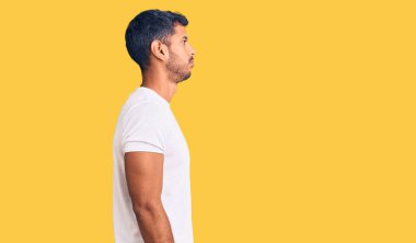 Gündelik kıyafetler giyen genç latin adam, rahat bir görünüm takınıyor, doğal bir yüz ve kendinden emin bir gülümsemeyle poz veriyor.. 