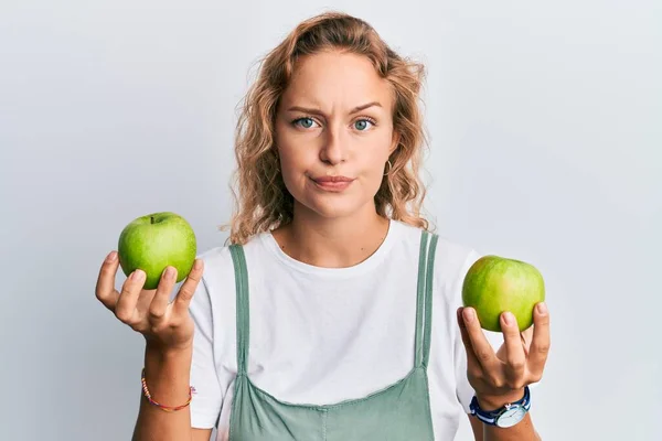 Όμορφη Καυκάσια Γυναίκα Κρατώντας Πράσινα Μήλα Σκεπτικός Και Νευρικός Συνοφρυωμένος — Φωτογραφία Αρχείου