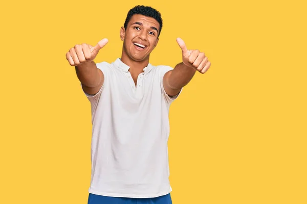 年轻的阿拉伯男子穿着休闲装 赞成用手做积极的手势 微笑着竖起大拇指 为成功感到高兴 优胜手势 — 图库照片