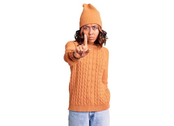 若い美しい混合レースの女性は ウールのセーターと冬の帽子を身に着けています指アップと怒りの表情で指しています ジェスチャーを示しません — ストック写真