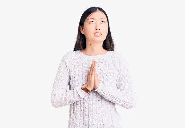 若い美しい中国の女性は 非常に感情的かつ心配の顔に希望の表現と一緒に手で物乞いや祈りのカジュアルなセーターを着て お願い — ストック写真