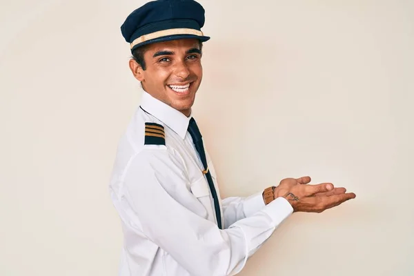 Mladý Hispánec Uniformě Pilota Letadla Ukazuje Stranou Rukama Otevřenýma Dlaněmi — Stock fotografie