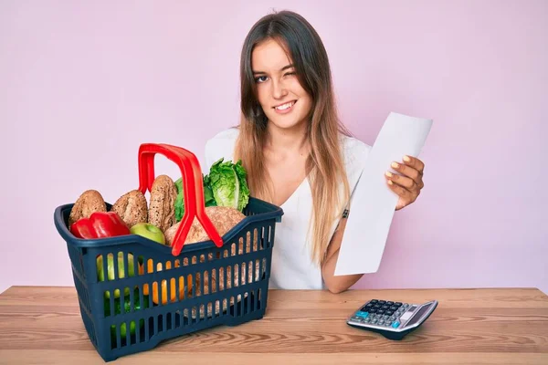 Beautiful Caucasian Woman Holding Supermarket Basket Groceries List Winking Looking — Stock Photo, Image