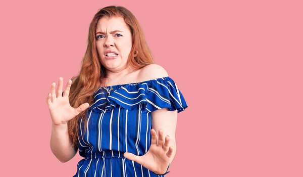 Young beautiful redhead woman wearing casual clothes disgusted expression, displeased and fearful doing disgust face because aversion reaction. with hands raised 