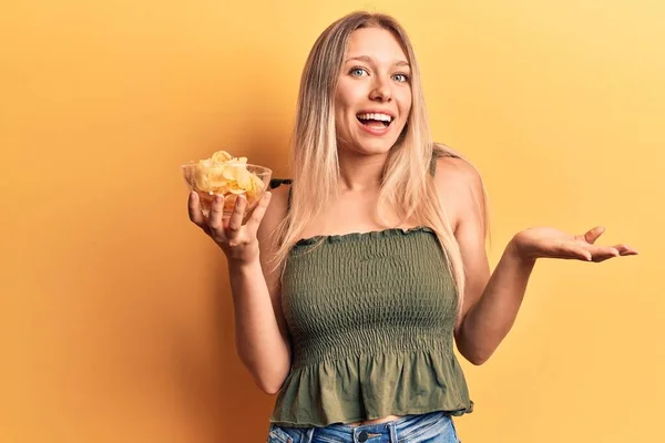 Patates Cipsi Tutan Genç Sarışın Kadın Başarıyı Mutlu Bir Gülümsemeyle — Stok fotoğraf