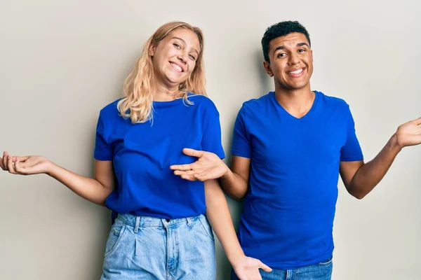 Young interracial couple wearing casual clothes smiling showing both hands open palms, presenting and advertising comparison and balance