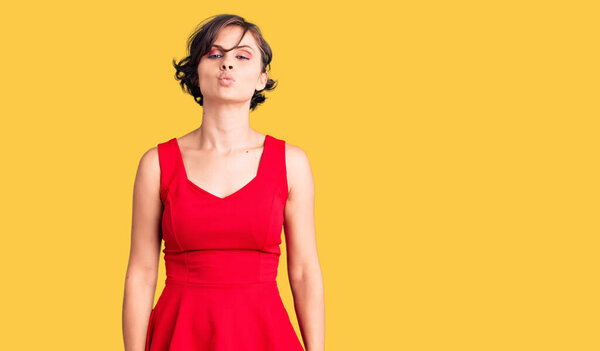 Beautiful young woman with short hair wearing casual style with sleeveless shirt looking at the camera blowing a kiss on air being lovely and sexy. love expression. 