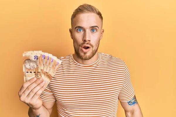 Güney Afrika 'nın 20 rand banknotunu elinde tutan beyaz bir genç. Şaşırtıcı bir şekilde korkmuş ve hayrete düşmüştü. İnanmayan yüz. 