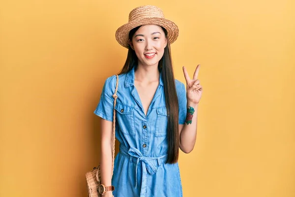 年轻的中国女人头戴夏帽 手指点点 面带微笑 自信而快乐 — 图库照片