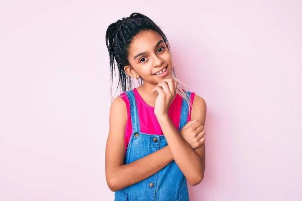ピンクの背景にカジュアルな服を着た若いアフリカ系アメリカ人の少女の子供は 交差した腕と手であごを上げて笑顔でカメラを見て自信を持っています ポジティブな — ストック写真
