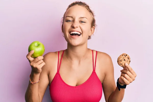 緑のリンゴとクッキーの笑顔を保持し 面白いクレイジー冗談ので大声で笑い美しい白人女性 — ストック写真