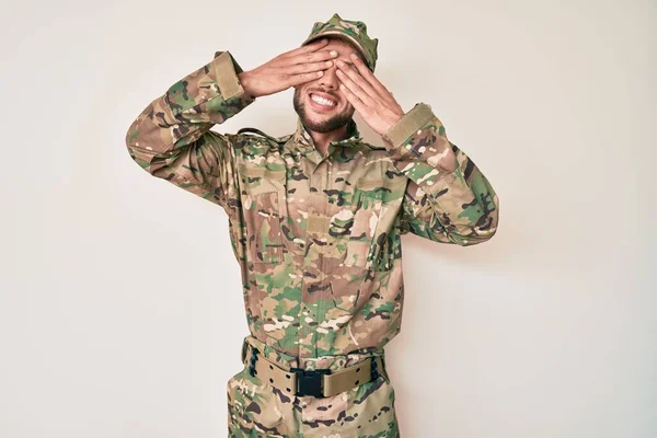 笑顔で陽気で面白い手で目を覆うカモフラージュ軍の制服を着た若い白人男性 視覚障害の概念 — ストック写真