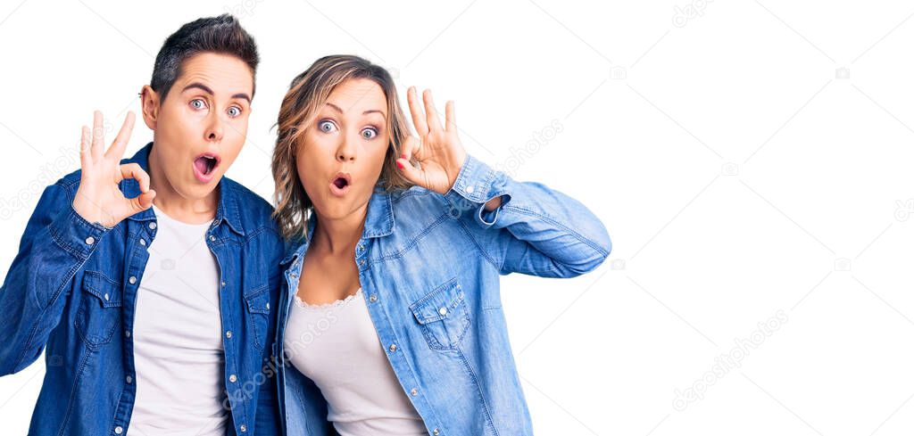 Couple of women wearing casual clothes looking surprised and shocked doing ok approval symbol with fingers. crazy expression 