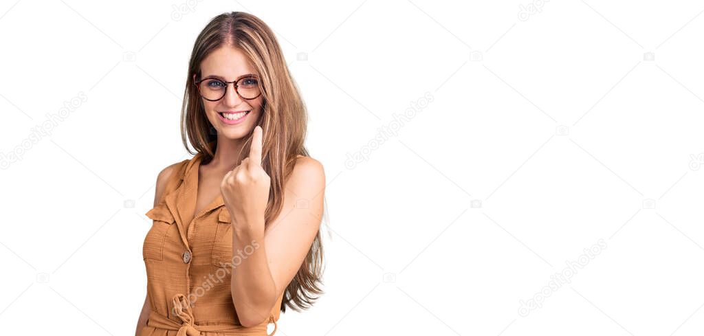 Young beautiful blonde woman wearing casual clothes and glasses beckoning come here gesture with hand inviting welcoming happy and smiling 