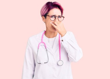 Pembe saçlı, doktor üniforması giyen genç bir kadın pis ve iğrenç bir koku alıyor. Dayanılmaz bir koku. Nefesini burnu havada tutuyor. Kötü kokuyor. 