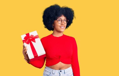 Genç Afrikalı Amerikalı kız elinde hediyeyle gülümseyip yan tarafa bakıyor ve şöyle düşünüyor:. 