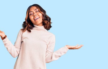 Balıkçı yaka kazak giyen genç ve güzel bir ırk kadını gülümseyerek avuçlarını açıyor, sunuyor ve reklam karşılaştırması yapıyor ve dengeyi sağlıyor. 