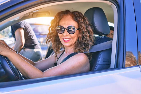 中年年轻漂亮的夫妇戴着太阳镜度假开着车快乐地微笑着 — 图库照片