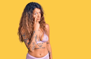 İç çamaşırlı, İspanyol bir kadın. Gözünü dikip jestini izliyor. Şüpheli bir ifade. 