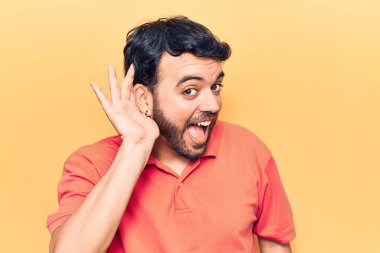 Gündelik kıyafetler giyen, ağzı kulaklarında gülümseyen, dedikoduları ve dedikoduları dinleyen genç İspanyol bir adam. Sağırlık kavramı. 