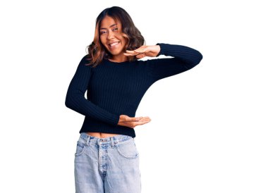 Genç, güzel, melez, sıradan kıyafetler giyen, elleri büyük ve büyük beden işareti olan bir kadın. Ölçü sembolü. Kameraya bakıp gülümsüyor. ölçüm kavramı. 