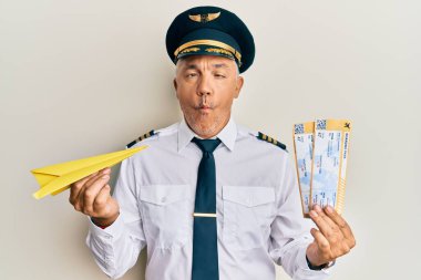 Yakışıklı orta yaşlı yetişkin pilot elinde kağıt uçak ve biniş kartıyla balık suratlı ve şaşı gözlü, çılgın ve komik.. 
