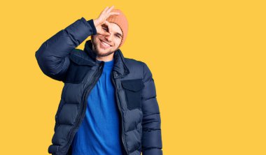 Kış kıyafetleri giyen yakışıklı adam gülümsüyor. Mutluluktan gülümsüyor. 