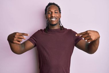 Saçları örgülü, kendine güvenen, gülümseyen, kendini gururlu ve mutlu gösteren Afro-Amerikan bir adam.. 