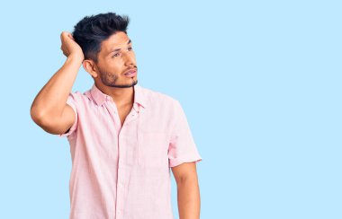 Gündelik tişört giyen yakışıklı Latin Amerikalı genç adamın kafası karışmış ve soru sormayı merak ediyor. Şüpheyle kararsız, kafa kafaya düşünerek. Düşünceli kavram. 