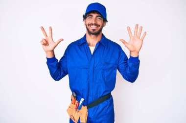 Kıvırcık saçlı ve ayı gibi giyinen yakışıklı genç adam sekiz numarayı gösterip işaret ederken kendinden emin ve mutlu gülümsüyor.. 