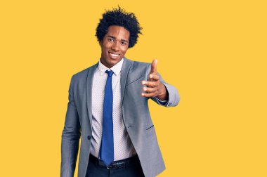 Afro saçlı, iş ceketi giyen yakışıklı Afro-Amerikan erkeği dostça bir şekilde el sıkışarak selamlıyor ve selamlıyor. başarılı iş. 