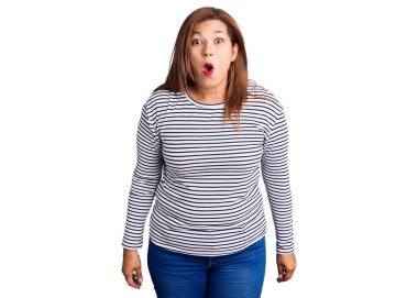 Orta yaşlı, sıradan kıyafetler giyen, ağzı açık, korkmuş, şaşırmış bir Latin kadın. 