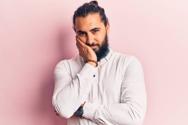 Gündelik kıyafetler giyen genç Arap adam kollarını kavuşturarak depresyondan yorgun ve sıkılmış göründüğünü düşünüyor.. 