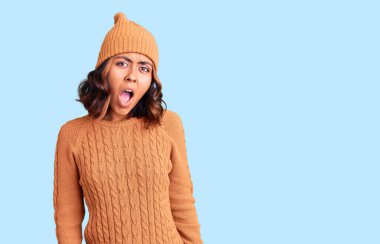 Şok suratlı, yün kazak ve kış şapkası giyen genç ve güzel bir ırk kadını şüpheci ve alaycı görünüyor, ağzı açık kalınca şaşırıyor. 