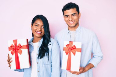 Güzel, genç, Latin bir çift yıldönümü kutlaması için hediye taşıyor. Olumlu ve mutlu görünüyorlar. Ve gülümsüyorlar. 
