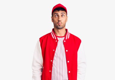 Beyzbol forması giyen genç İspanyol adam dudaklarıyla balık suratı yapıyor, çılgınca ve komik bir jest. Komik ifade. 