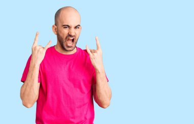 Genç yakışıklı adam, sıradan tişörtler giyip çılgın bir ifadeyle bağırıyor ve elleri havada rock sembolü yapıyor. Müzik yıldızı. ağır kavram. 