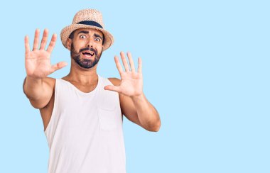Yaz şapkası takan Latin kökenli genç adam korku ifadesinden korkmuş ve dehşete düşmüş. El kol hareketi yapmayı kes, şok içinde bağır. panik konsepti. 