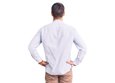 Zarif bir iş gömleği ve gözlüklü yakışıklı genç adam kolları vücudunda geriye doğru bakıyor. 