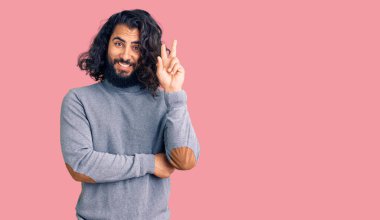 Gündelik kıyafetler giyen genç bir Arap kameraya gülümseyen ve zafer işareti yapan bir adam. İki numara.. 