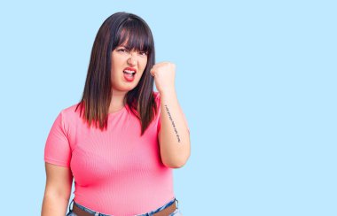 Genç ve cüsseli bir kadın, kızgın ve kızgın. Öfkeyle bağırırken yumruğunu sallıyor ve öfkeleniyor. öfke ve agresif konsept. 