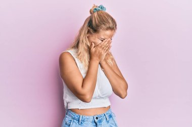 Genç, sarışın, sıradan kıyafetler giyen, suratını ellerle kapatıp ağlayan bir kız. depresyon kavramı. 