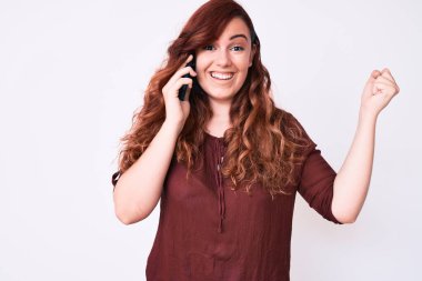 Genç ve güzel bir kadın akıllı telefonda konuşuyor gururla bağırıyor, zaferi kutluyor ve kollarını kaldırarak çok heyecanlanıyor. 