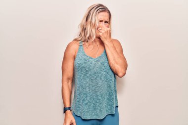 Orta yaşlı beyaz kadın spor giysisi giyiyor. Kokuşmuş ve iğrenç bir koku alıyor. Dayanılmaz bir koku. Kötü kokuyor. 