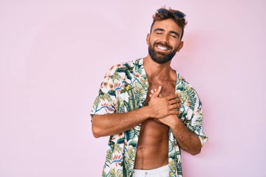 Latin kökenli genç bir adam, günlük kıyafetlerini giymiş, eli açık, dur işareti yapıyor, ciddi ve kendinden emin bir ifadeyle, savunma hareketi yapıyor. 