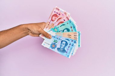 Hispanik el ele tutuşma Çin Yuan banknotları kapalı pembe arka plan.
