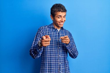 Sıradan kıyafetler giymiş genç Afro-Amerikalı adam mutlu ve komik yüzüyle kamerayı işaret ediyor. iyi enerji ve titreşimler. 