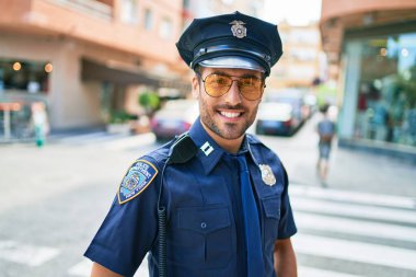 Polis üniforması giyen genç, yakışıklı İspanyol polis mutlu bir şekilde gülümsüyor..