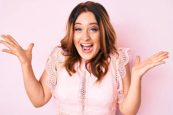 Güzelim beyaz kadın gündelik kıyafetler giyip zaferi mutlu bir gülümsemeyle ve ellerini kaldırarak kazanan ifadeyle kutluyor. 